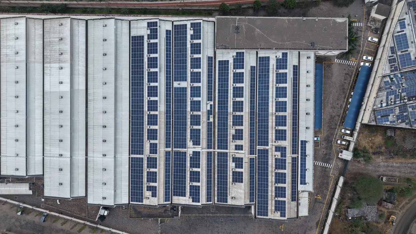 Overhead drone view of solar panel rows on the multi-bay roof of a high-security printing and assembly facility
