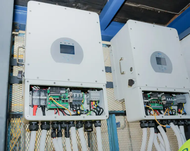 Two hybrid solar inverters with open wiring compartments during a battery storage installation